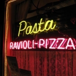 It's a neon sign. It says Pasta, Ravioli - Pizza. It glows.