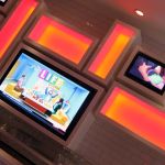 The wall behind the bar. Evangelion is playing on the upper TV.