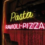 It's a neon sign. It says Pasta, Ravioli - Pizza. It glows.