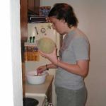 Trying to add excitement to her stirring job, Emily tries holding a cantaloupe to pass the time.